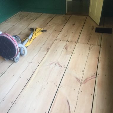 wood floor planks with sanding machine on top