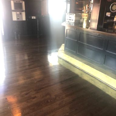 bar area with dark brown hardwood flooring, sun shining brightly through window